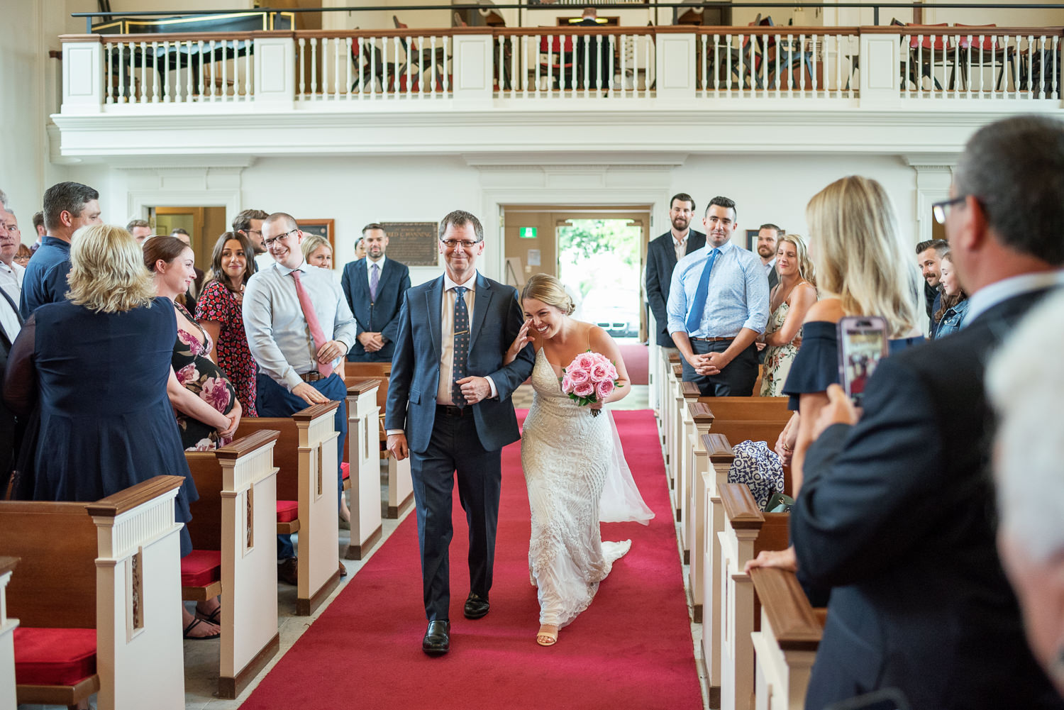 bride and father walk down the aisle during chapel wedding at acadia university