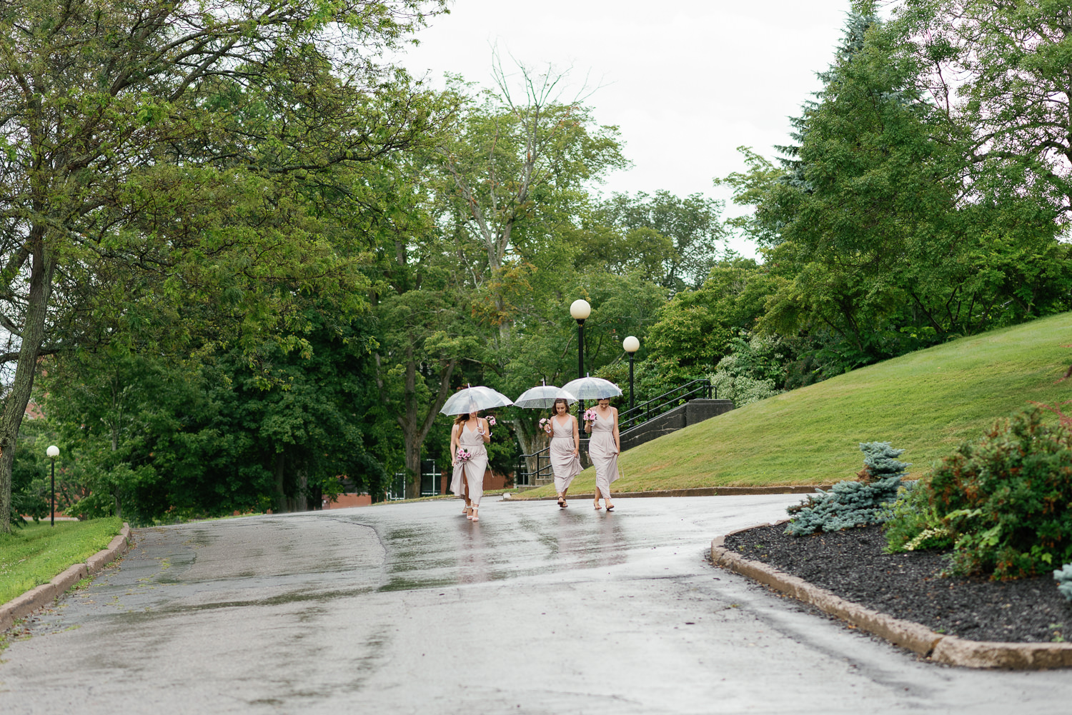 bridesmaids walk in the rain around acadia university campus