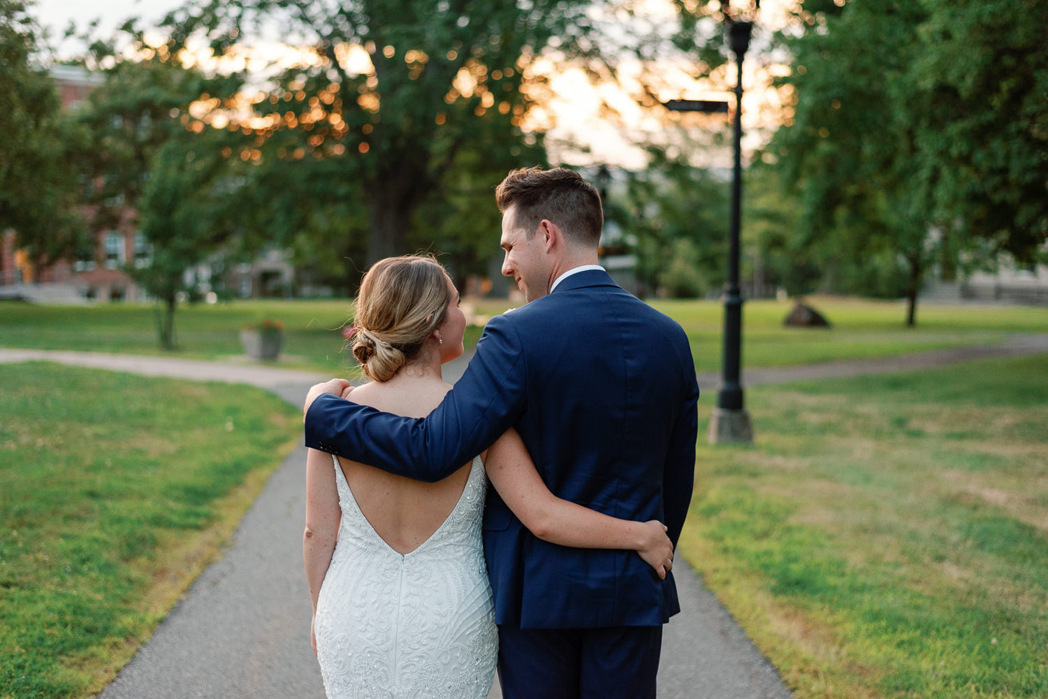 bride and groom walking around acadia campus grounds at sunset