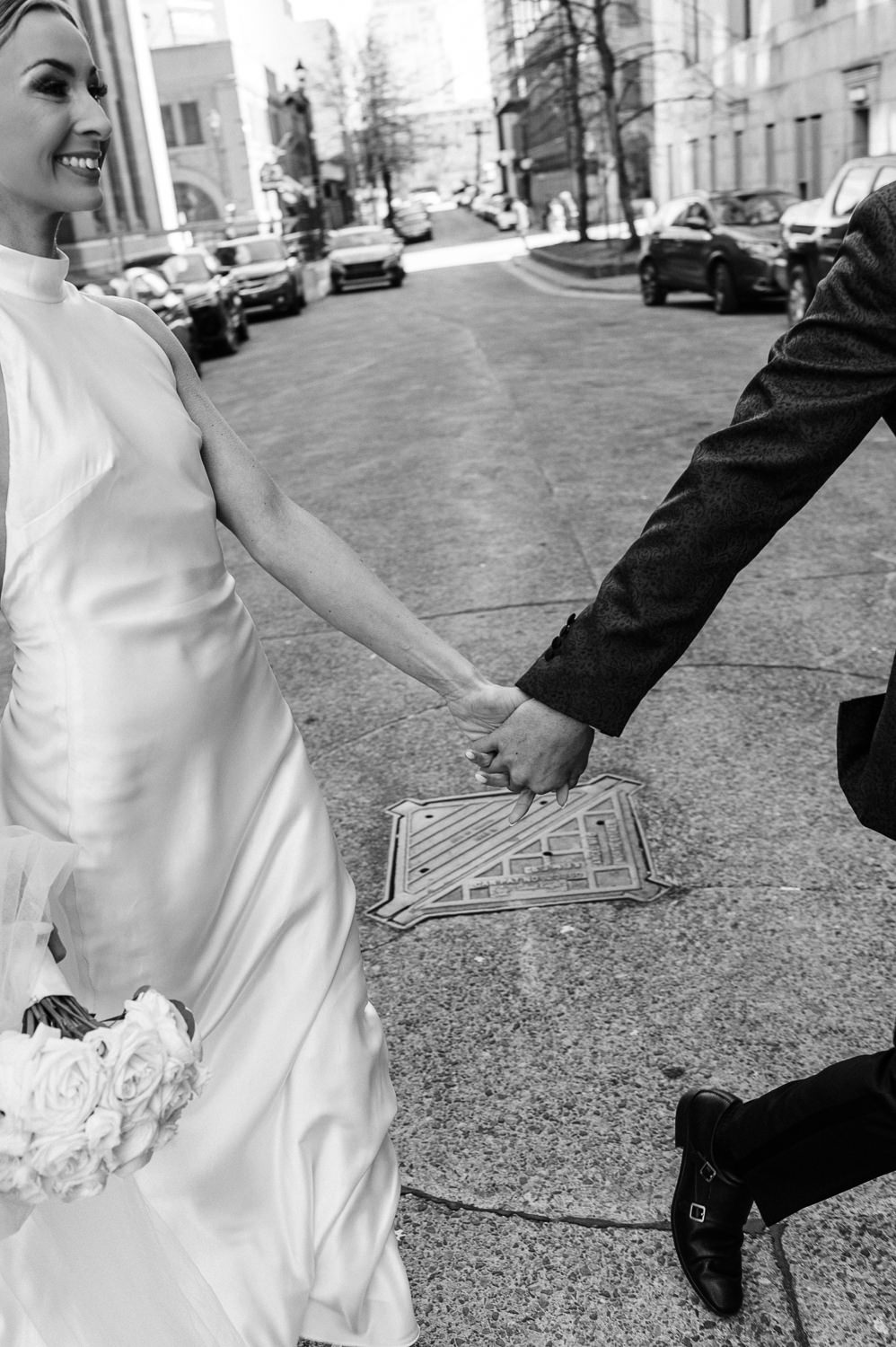 Bride and groom laugh joyfully as they cross the street in downtown Halifax