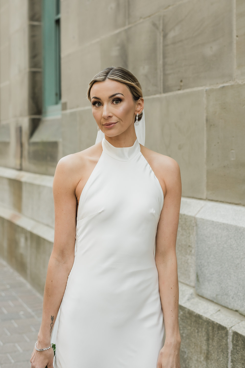 Stylish bride poses in front of beige stone building in downtown Halifax