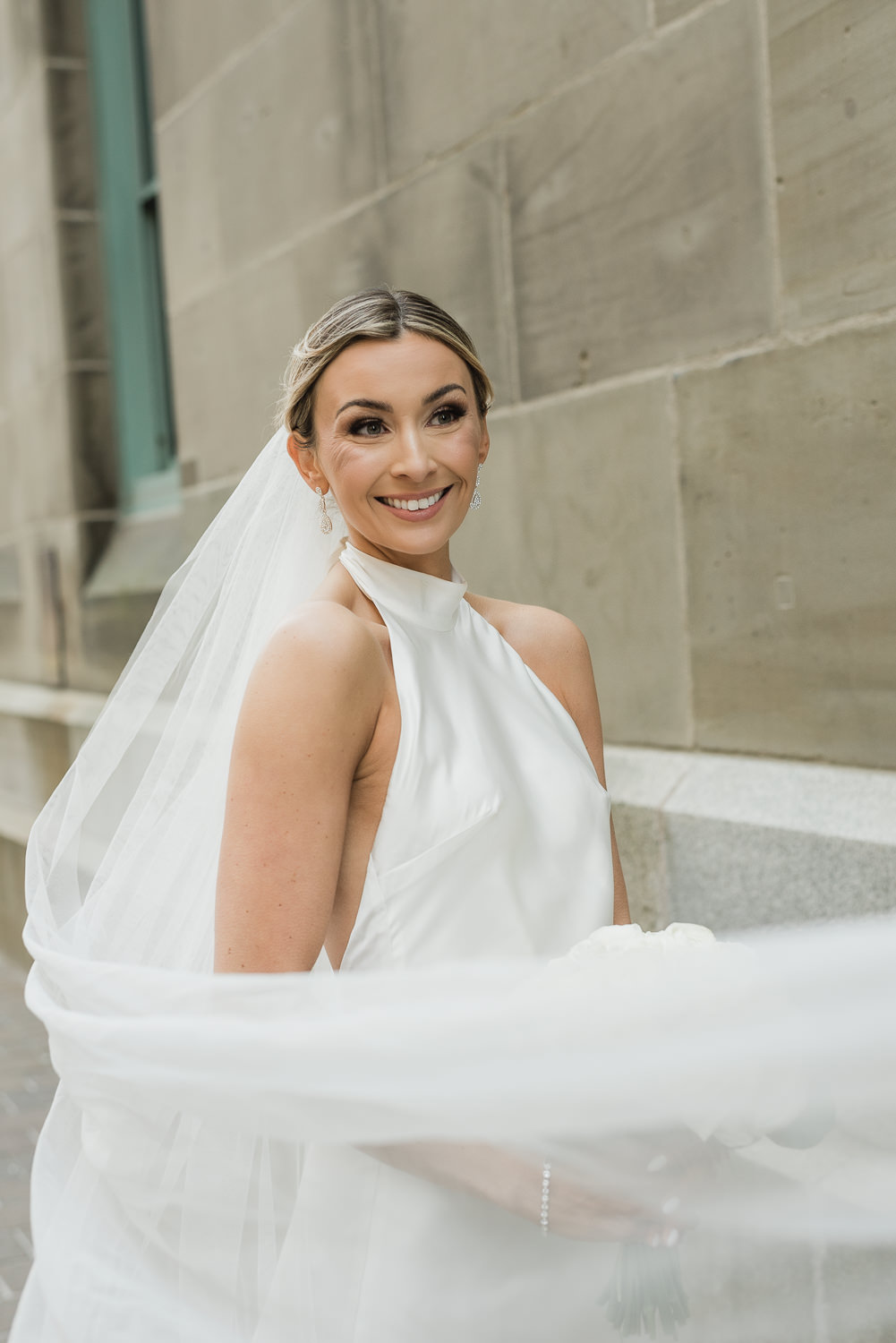 Stylish bride poses in front of beige stone building in downtown Halifax