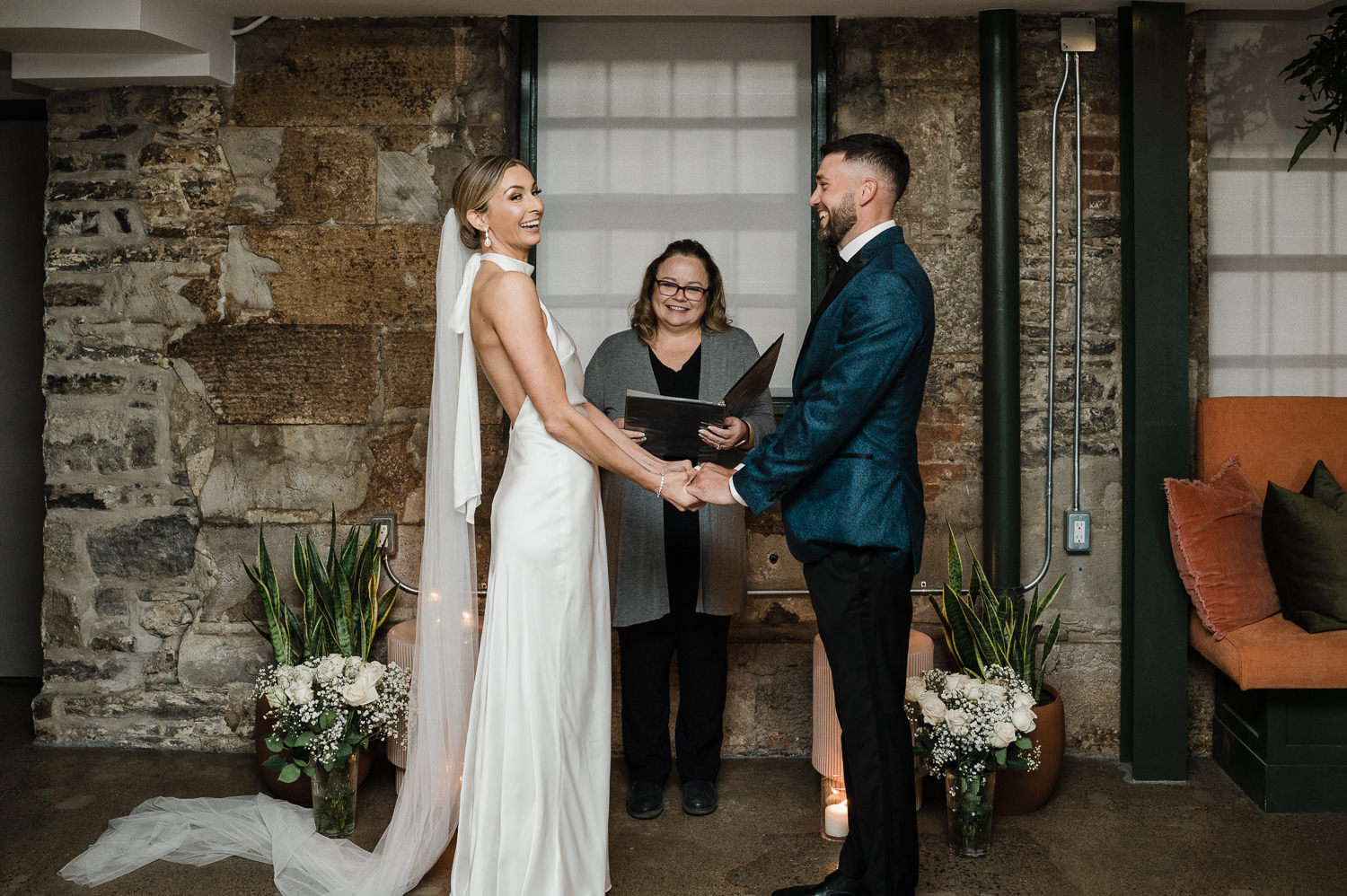 Bride and groom stand together while family watches them get married during ceremony at Anemone Dining