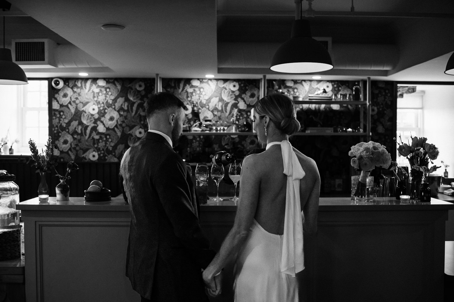 Bride and groom share a glass of wine at the bar of Anemone Dining during their wedding reception