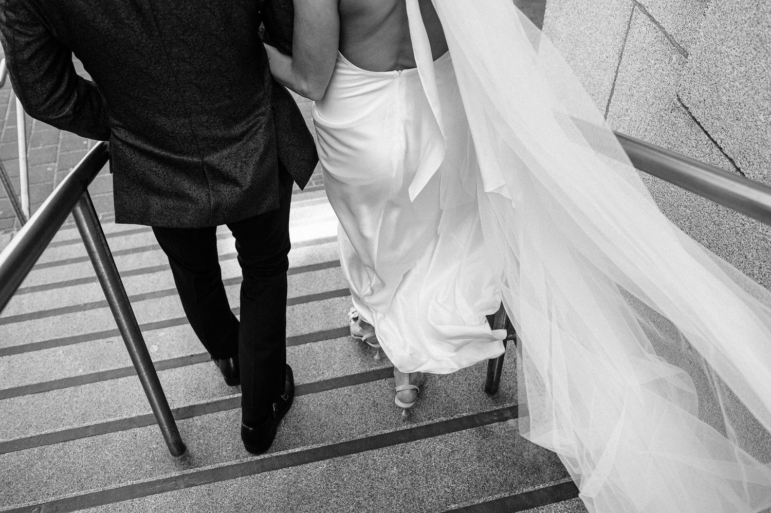 Bride and groom walk down the steps of AGNS while wind blows the dress and veil