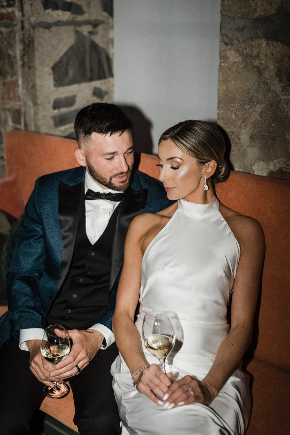 Flash photography of stylish bride and groom sharing a toast with wine glasses at Anemone Dining.