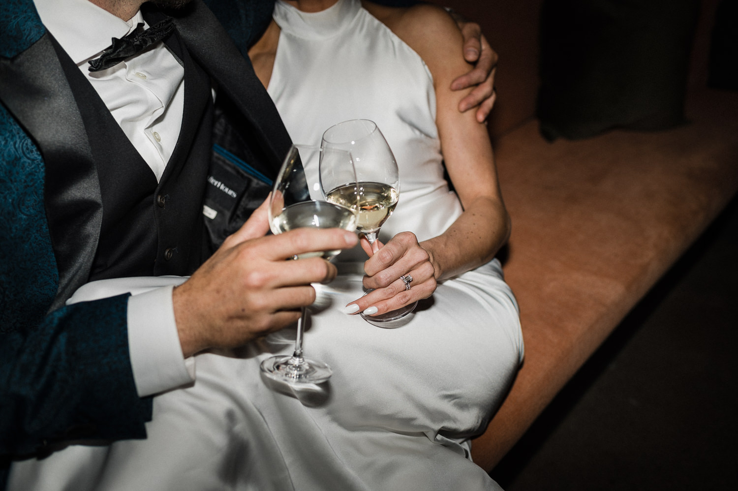 Flash photography of stylish bride and groom sharing a toast with wine glasses at Anemone Dining.