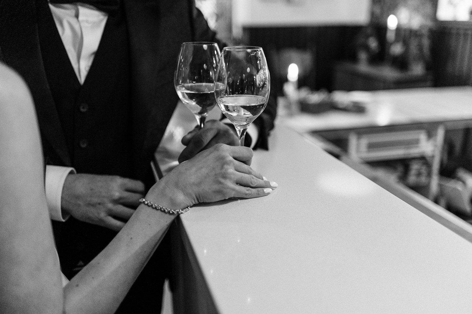 Bride and groom share a glass of wine at the bar of Anemone Dining during their wedding reception