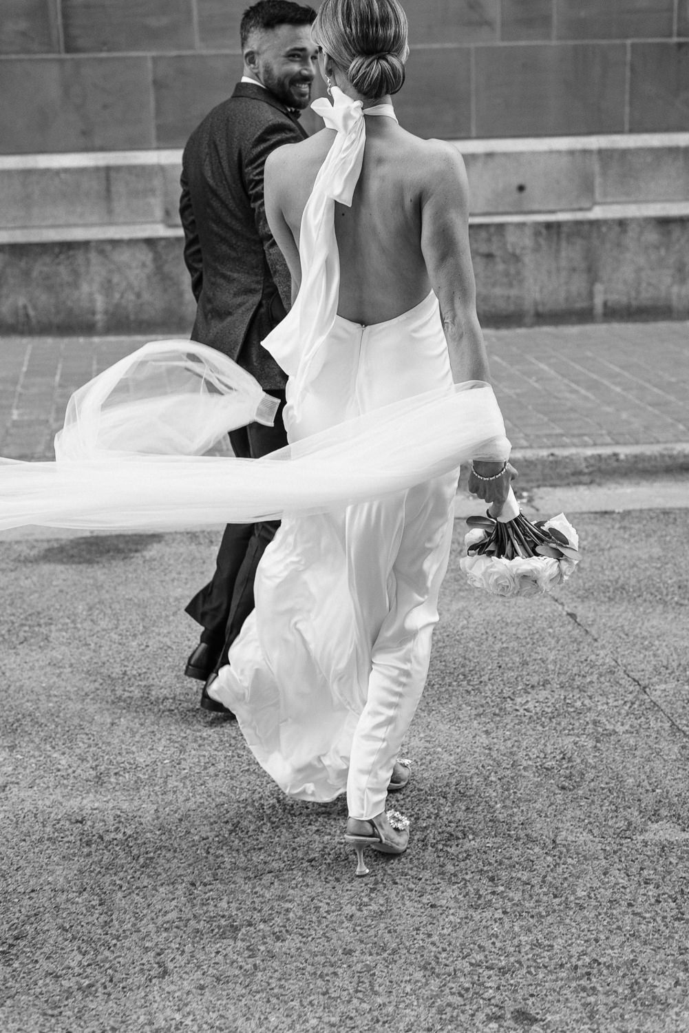 Bride's veil blows out of her hair as she crosses the street in downtown Halifax