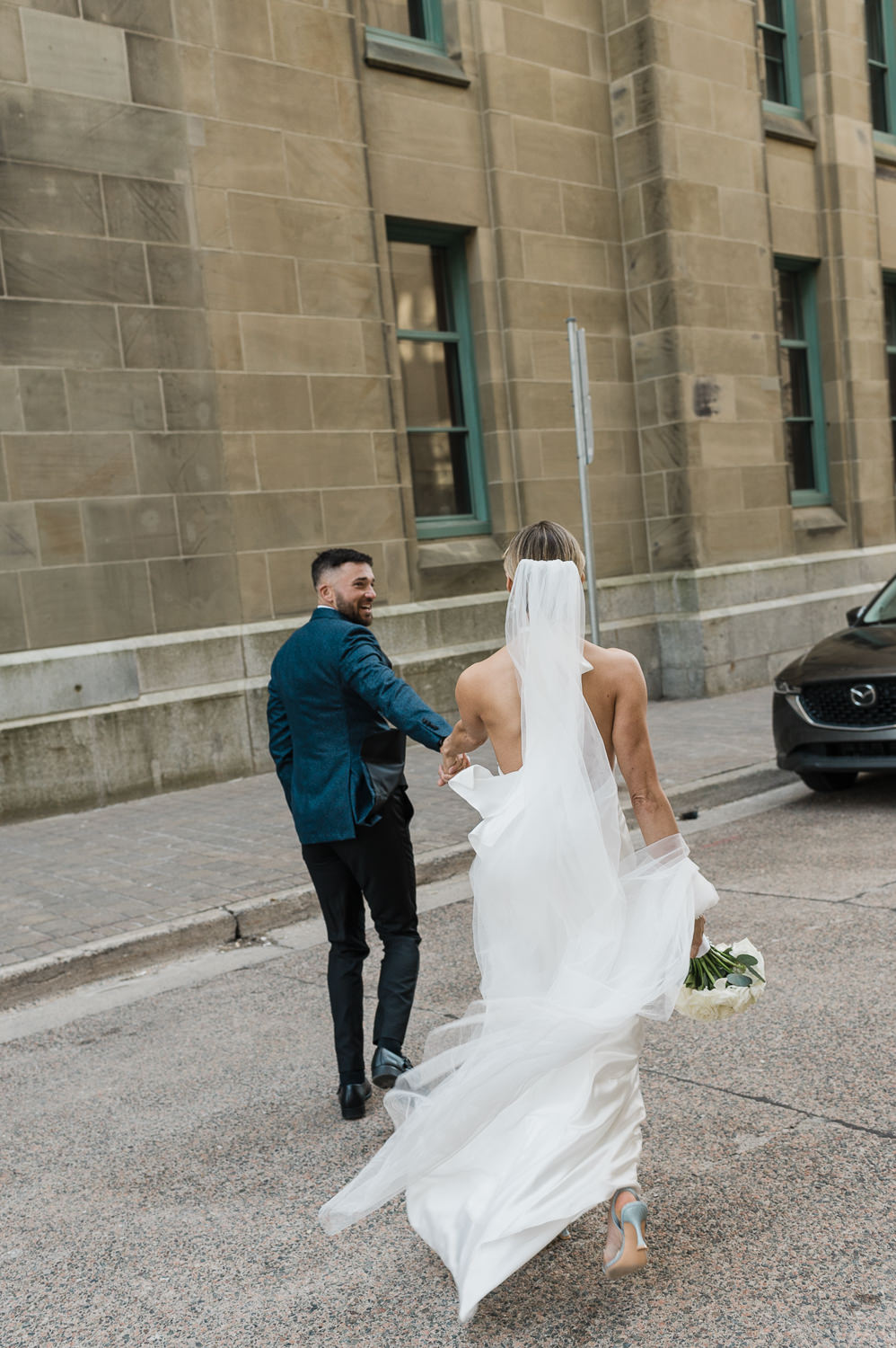 Bride and groom cross quiet street in downtown Halifax