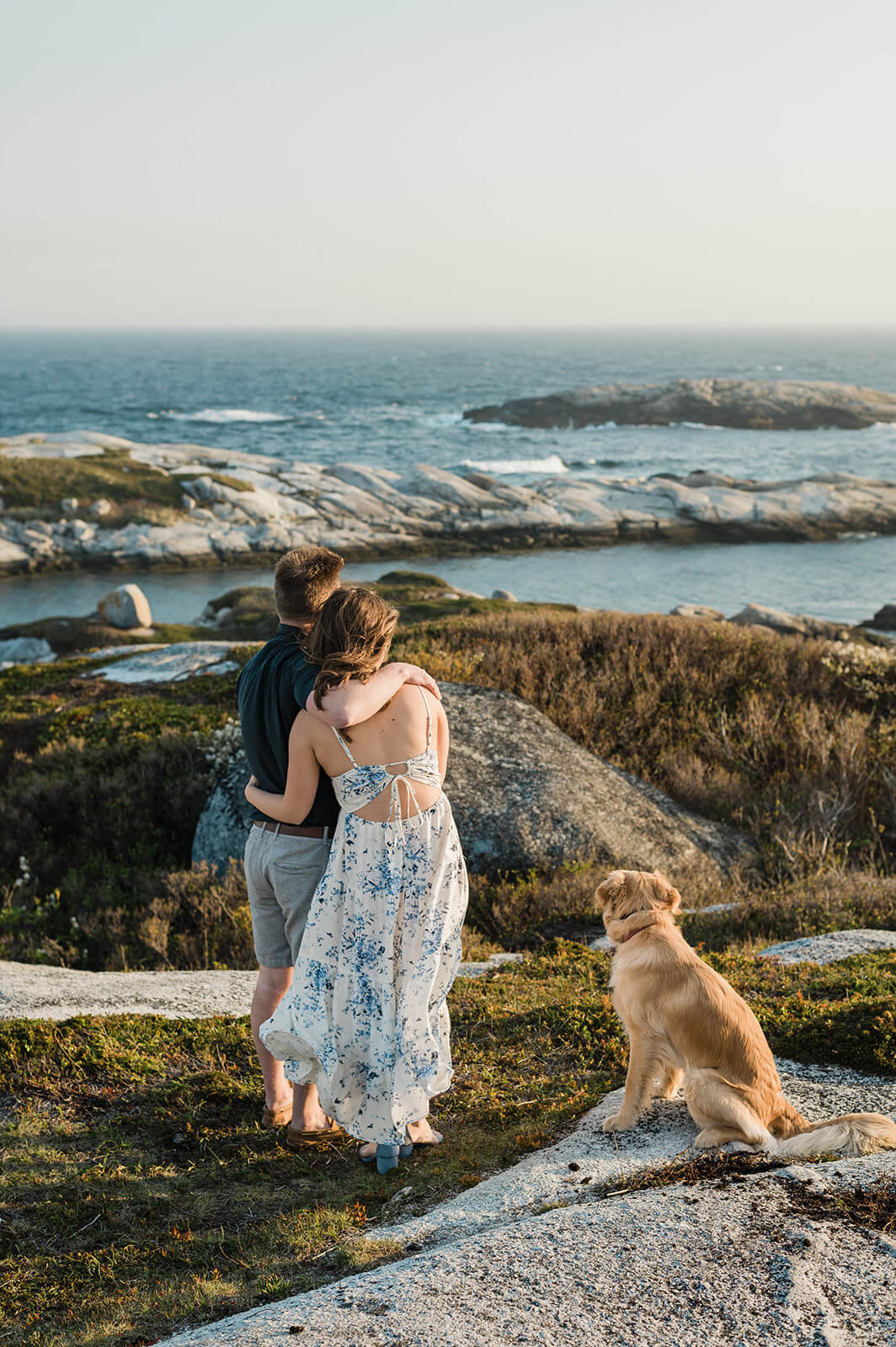 couple pose with their dog for engagement photos at Polly's Cove