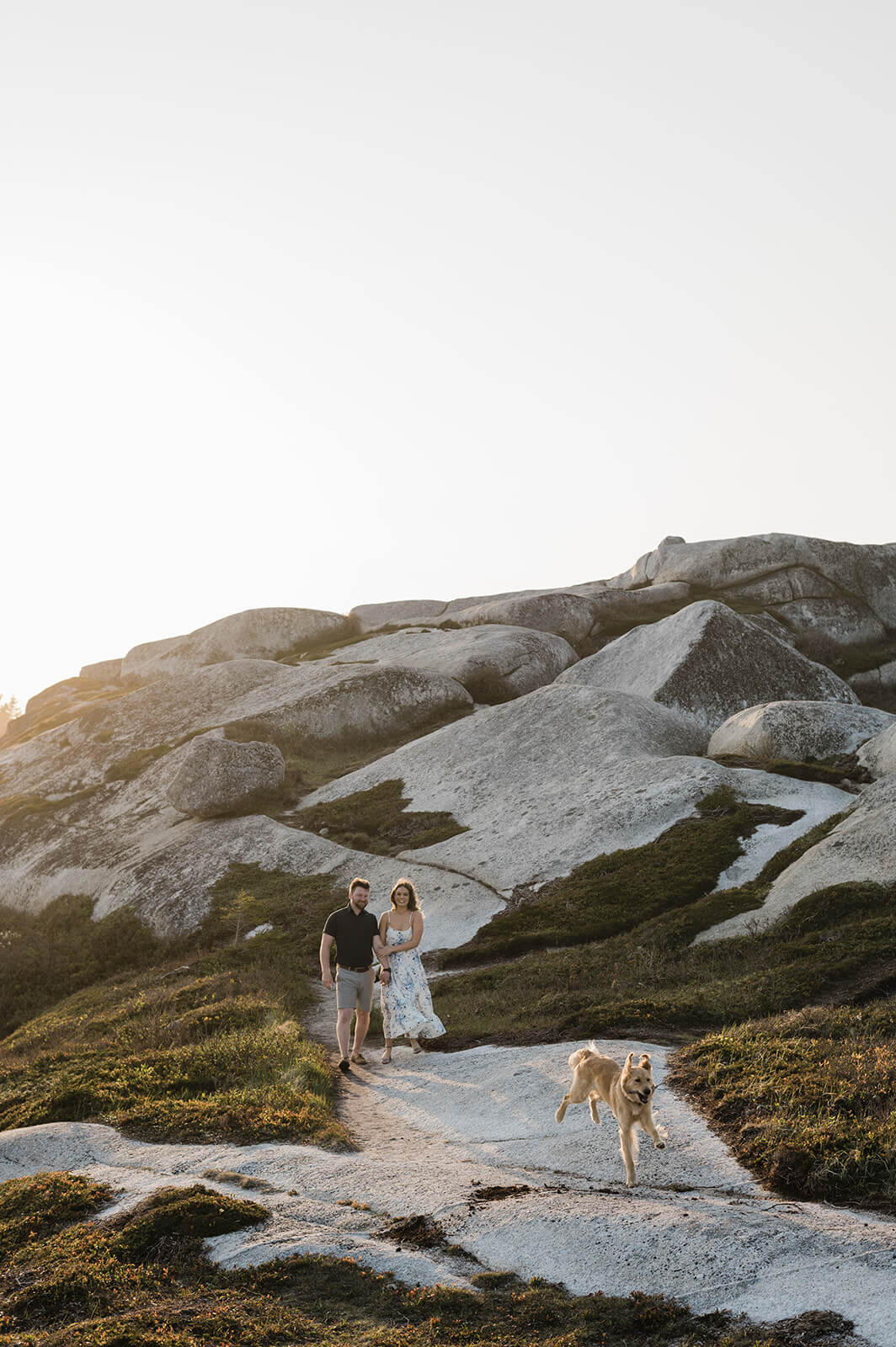 couple pose with their dog for engagement photos at Polly's Cove