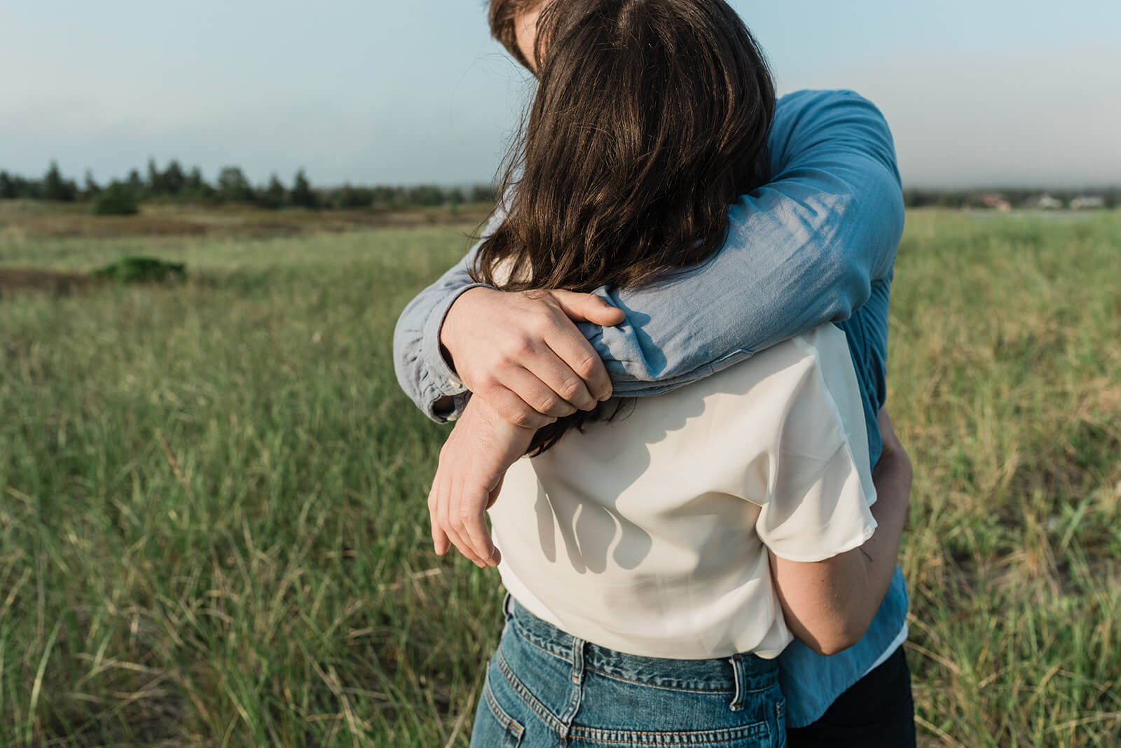 Couple embrace during engagement session on Rainbow Haven beach