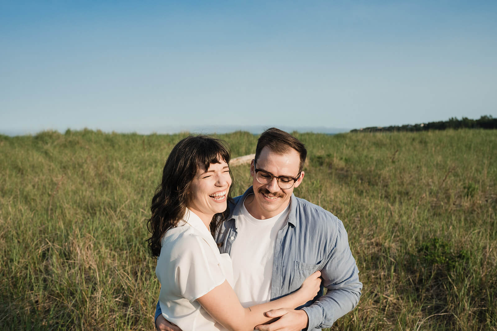 Couple embrace during engagement session on Rainbow Haven beach