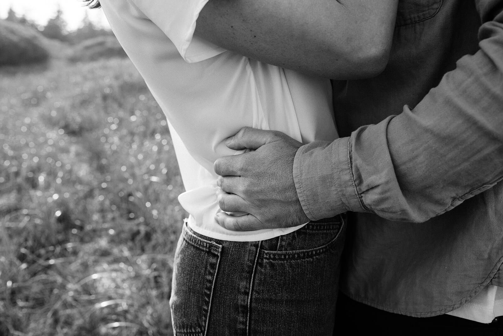 Couple embrace during engagement session on Rainbow Haven beach