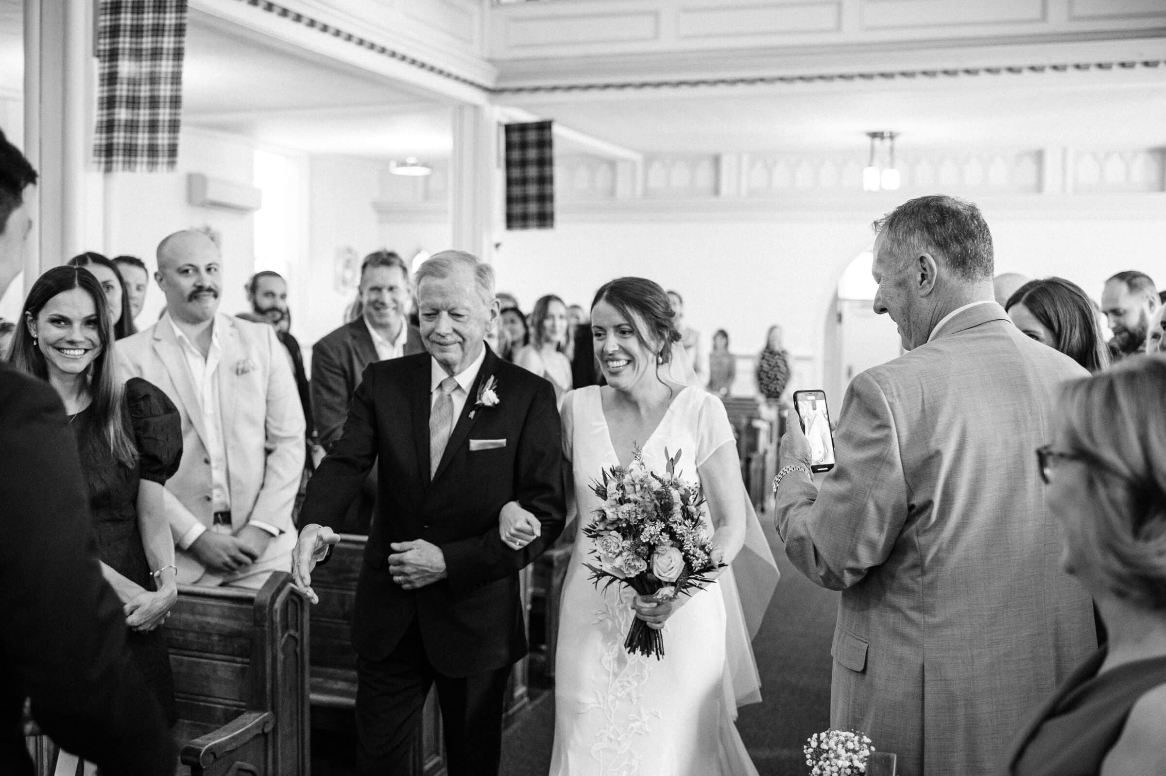 bride walks down church aisle with father