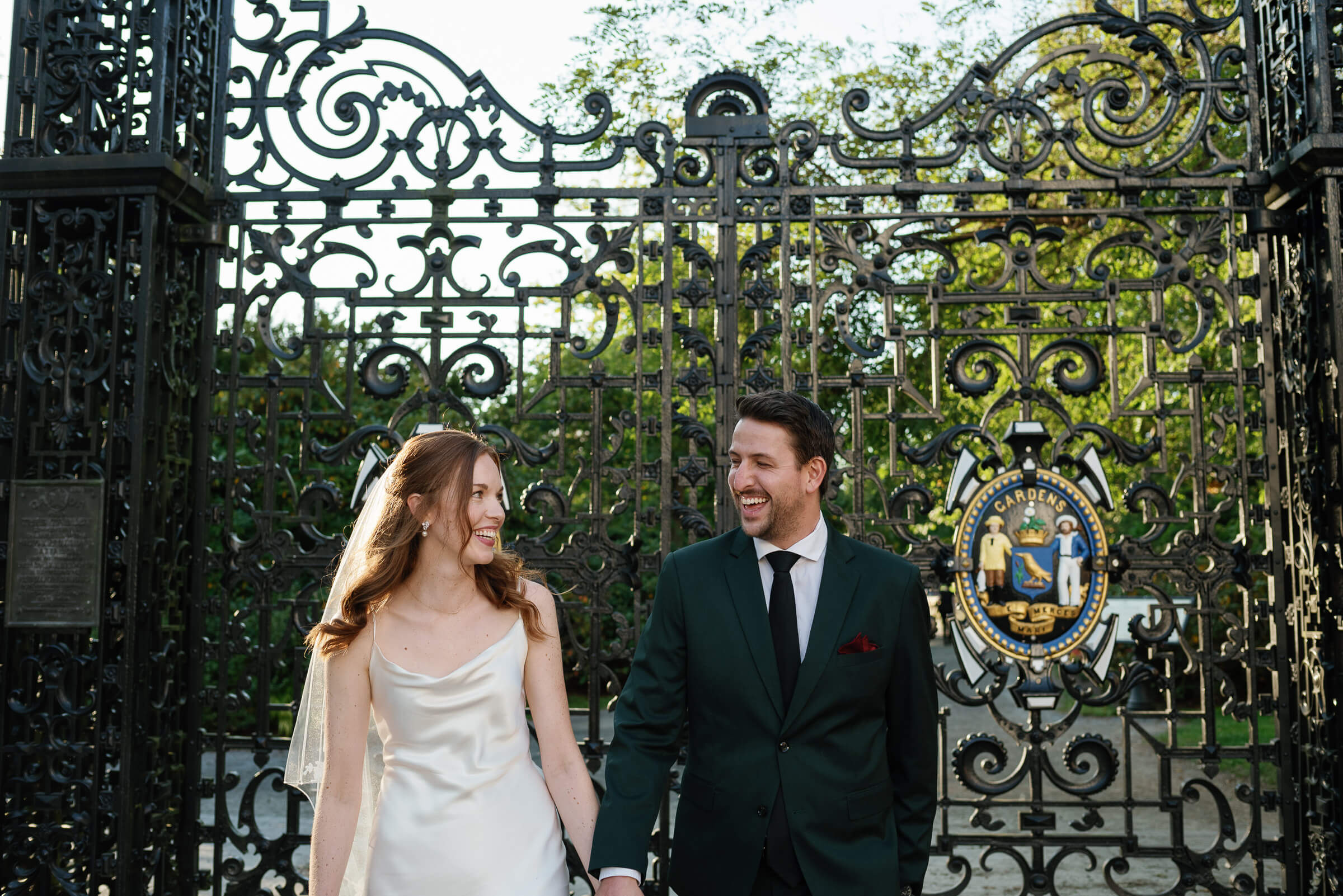 bride and groom smile outside the gate of halifax public gardens