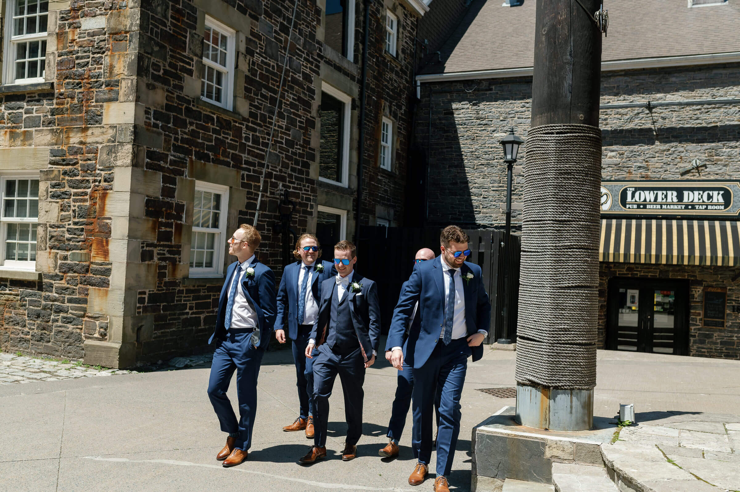 groomsmen dressed in blue suits walk around the halifax waterfront for portraits