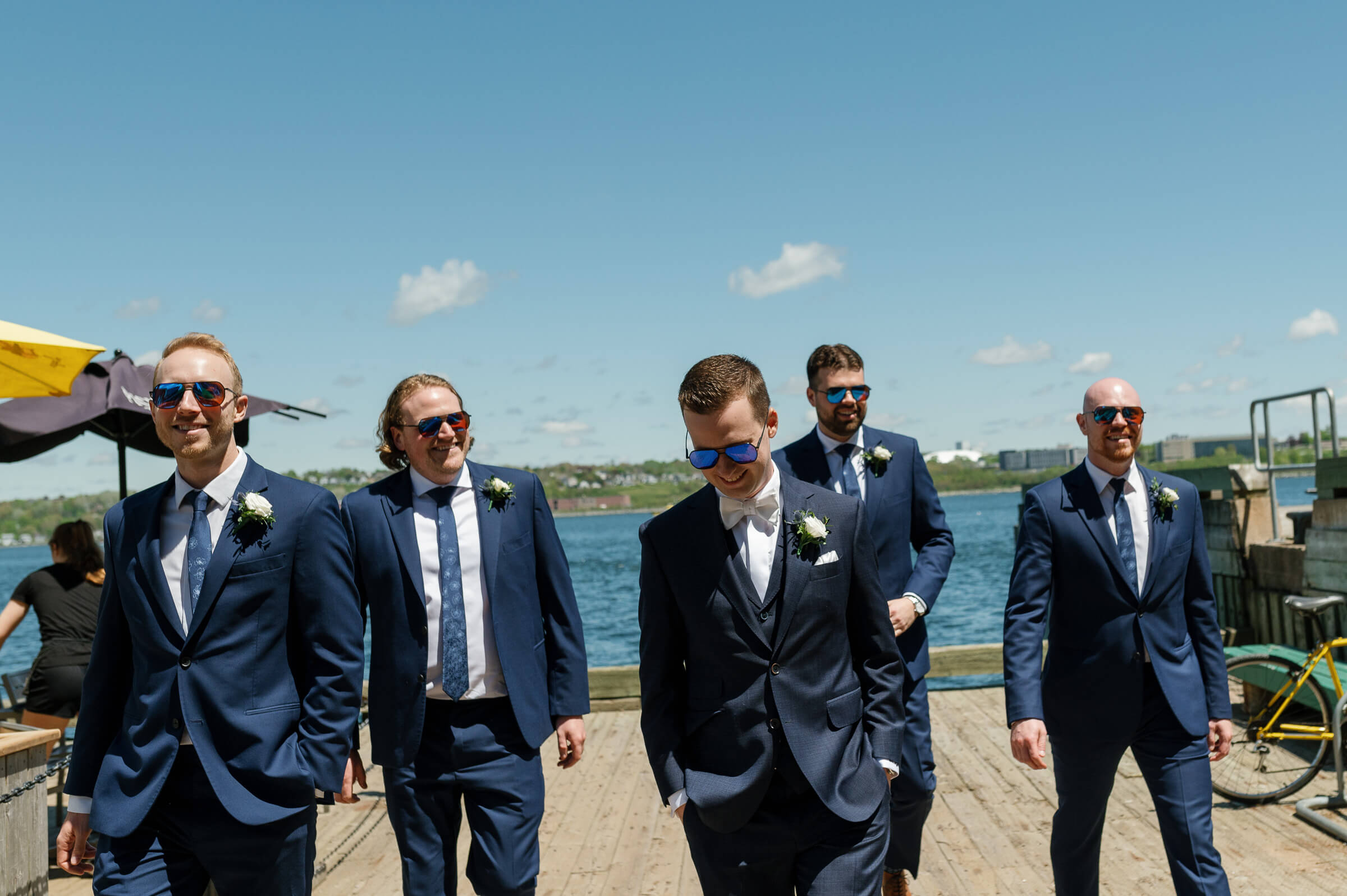 groomsmen dressed in blue suits walk around the halifax waterfront for portraits