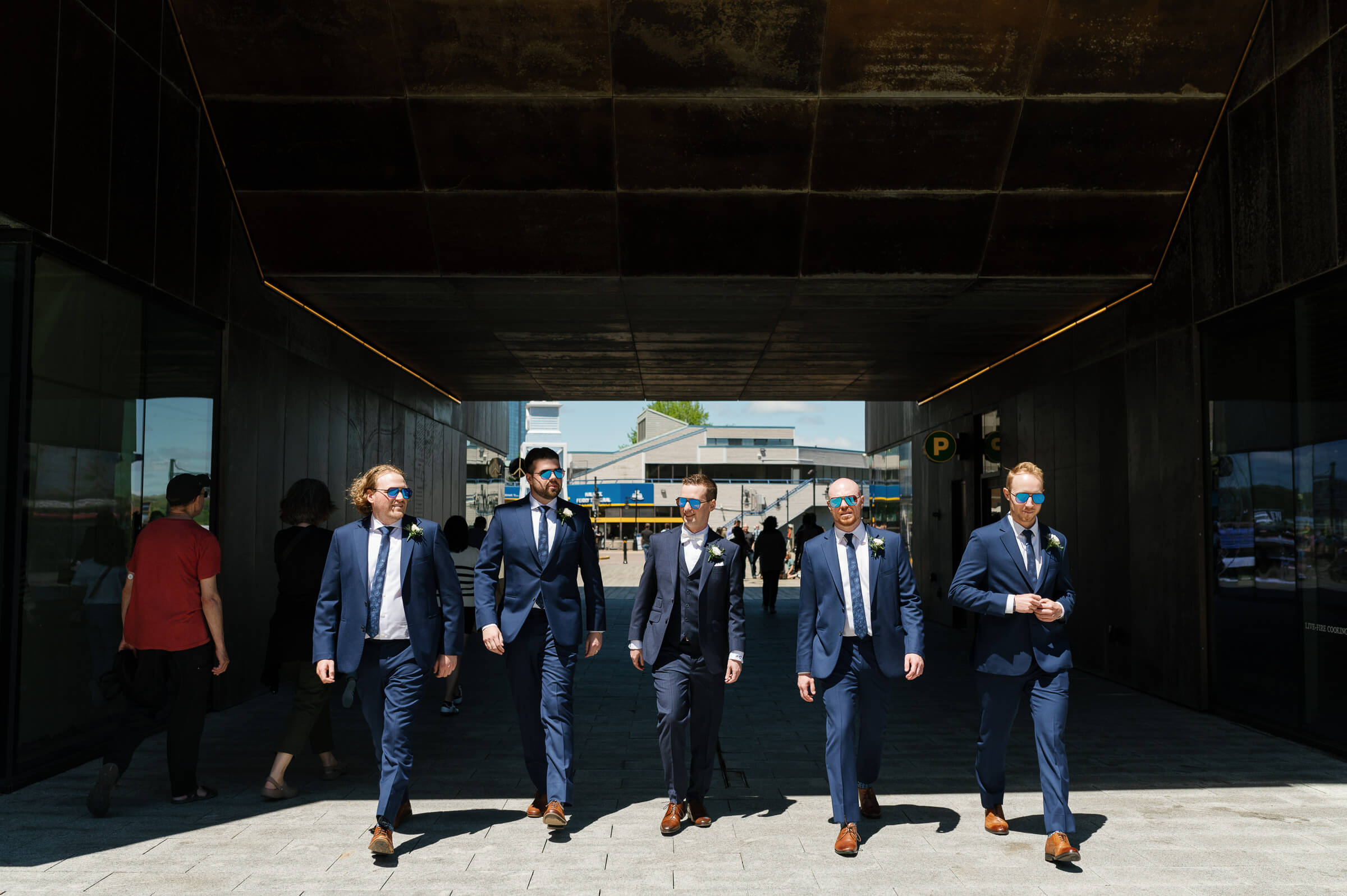 groomsmen dressed in blue suits walk around the halifax waterfront for portraits